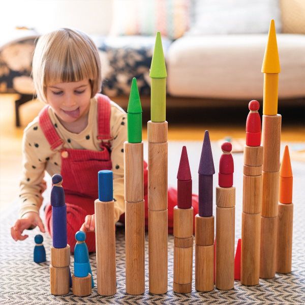 Little girl playing with Grimm's Large Natural Rollers Griends and Rainbow Forest