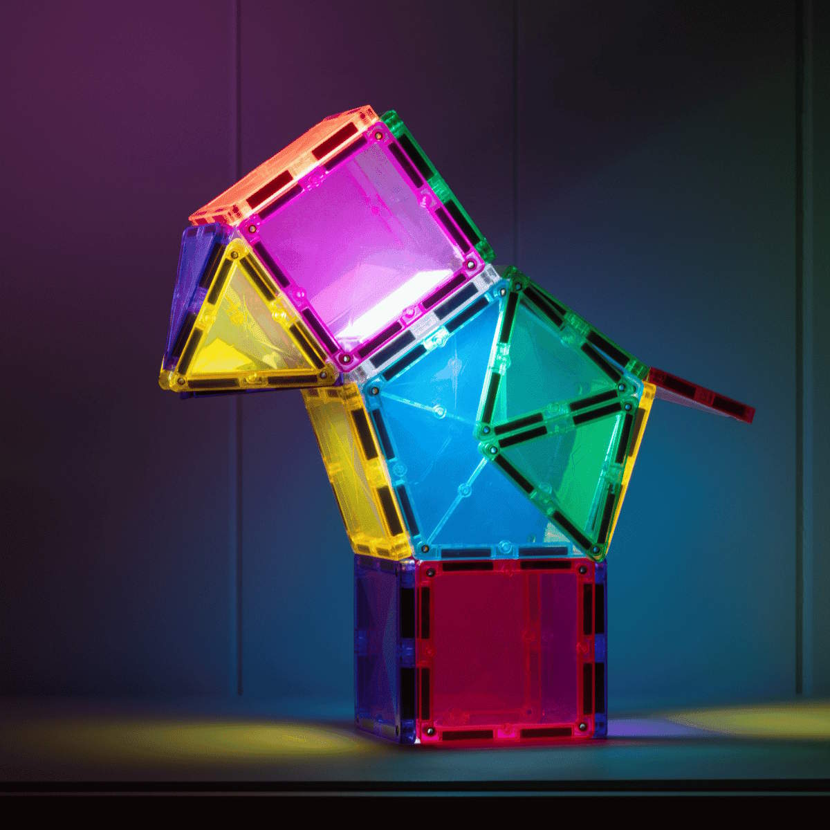 Colorful magnetic building tiles creating a bird shape that&#39;s been lit from the inside stacked on a dark background