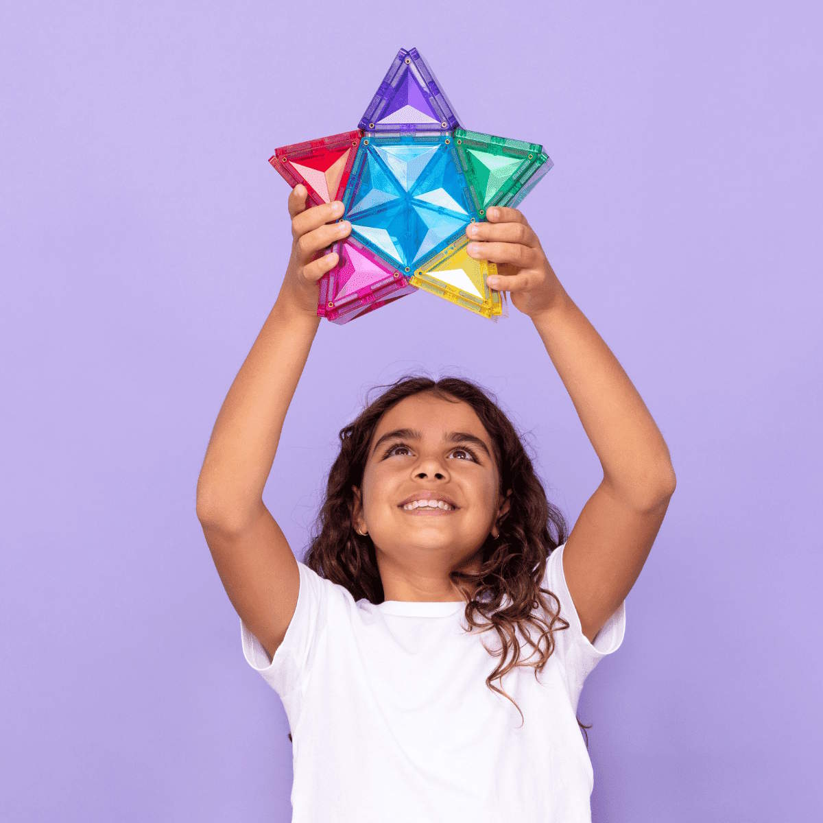 Child holding a colorful Connetix Magnetic Tiles star against a purple background