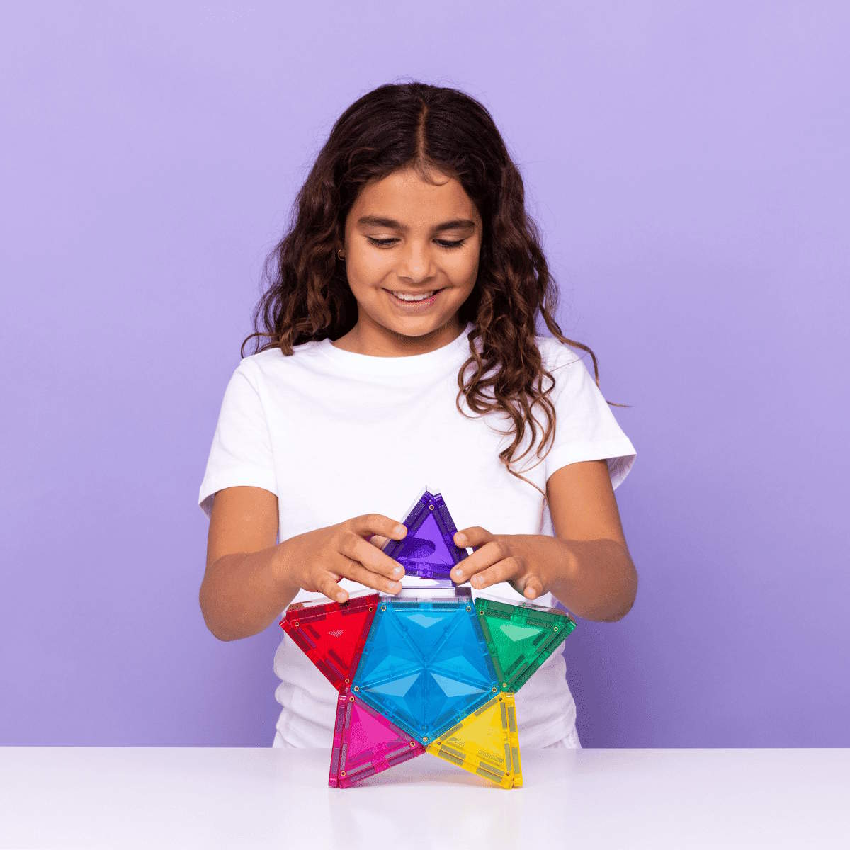 Girl holding colorful geometric shapes against a purple background