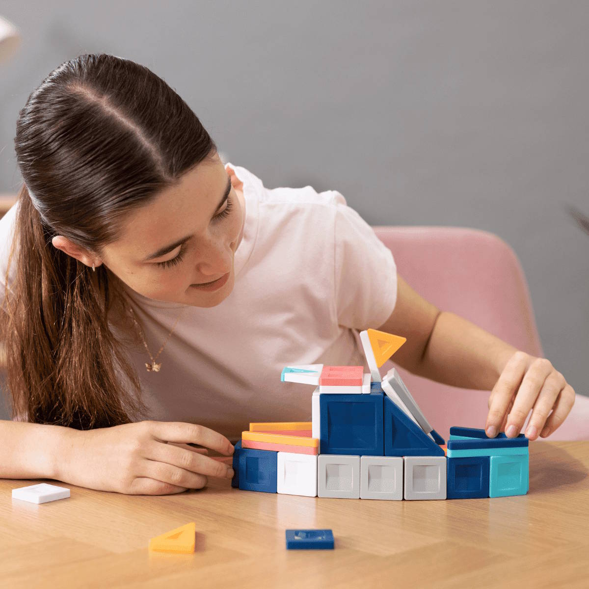 Older child playing with colorful magnetic building tiles from Connetix PRO on a table