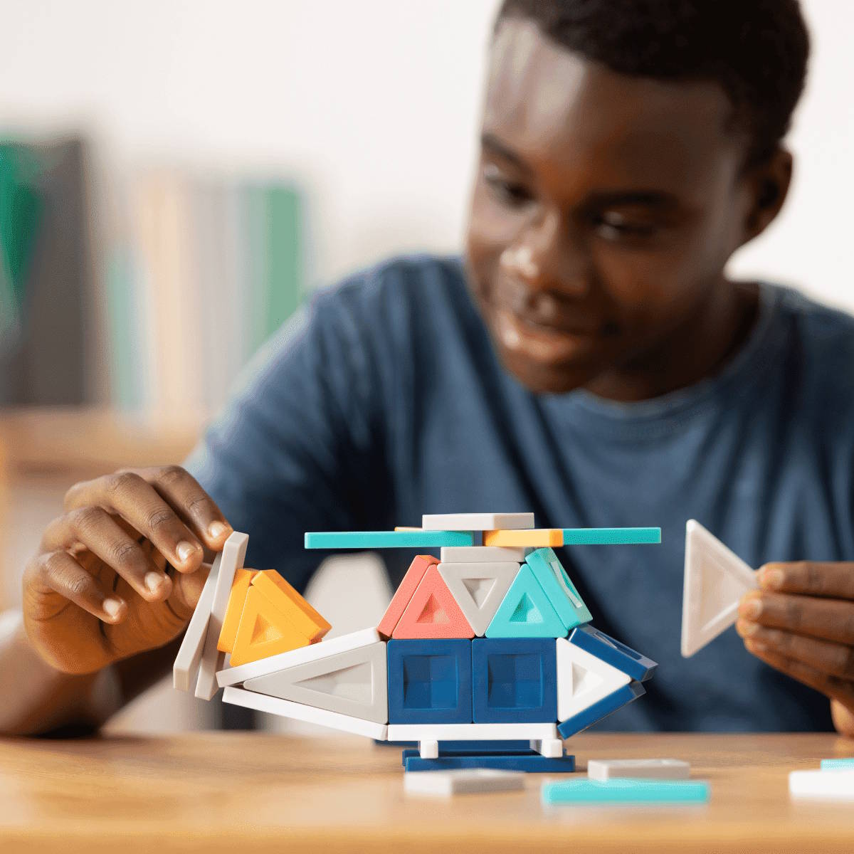 Child playing with geometric building tiles on a wooden table