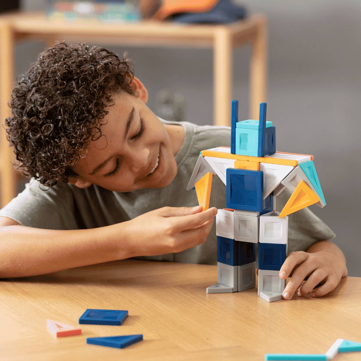 Child playing with a colorful geometric building set on a wooden table.