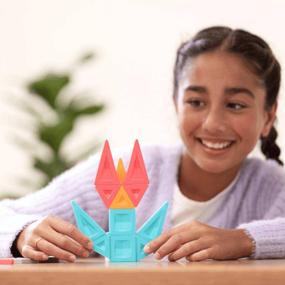 Older child playing with colorful magnetic tiles at a table