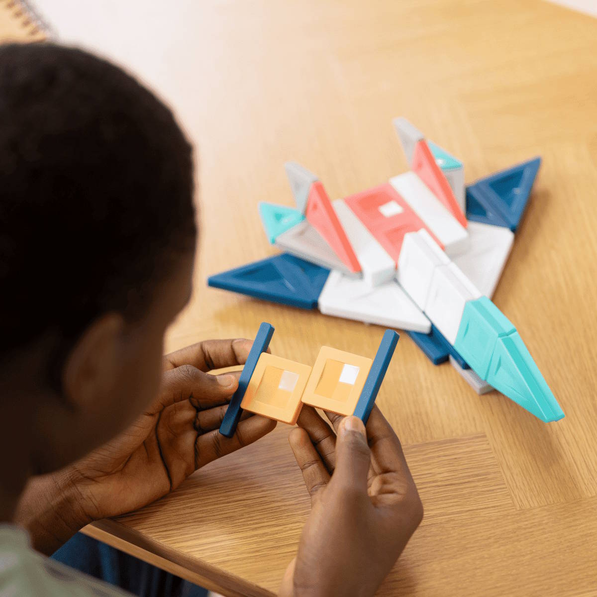 Child playing with geometric shapes on a wooden table