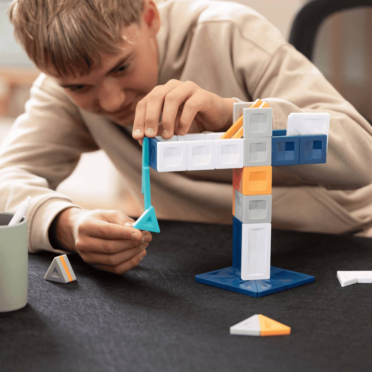 Child playing with a toy magnetic construction set on a dark surface
