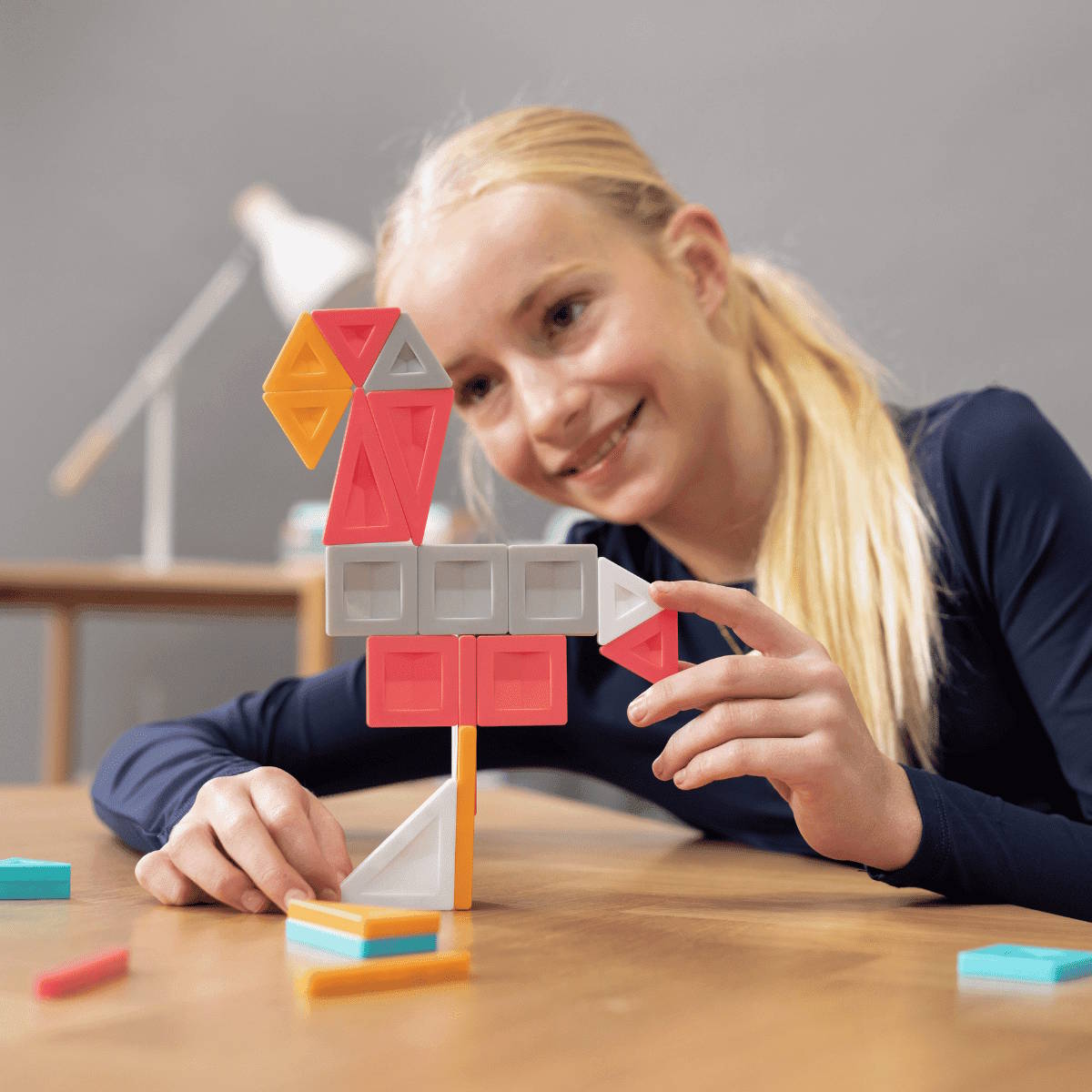 Young girl playing with colorful Connetix Pro magnetic building tiles on a table