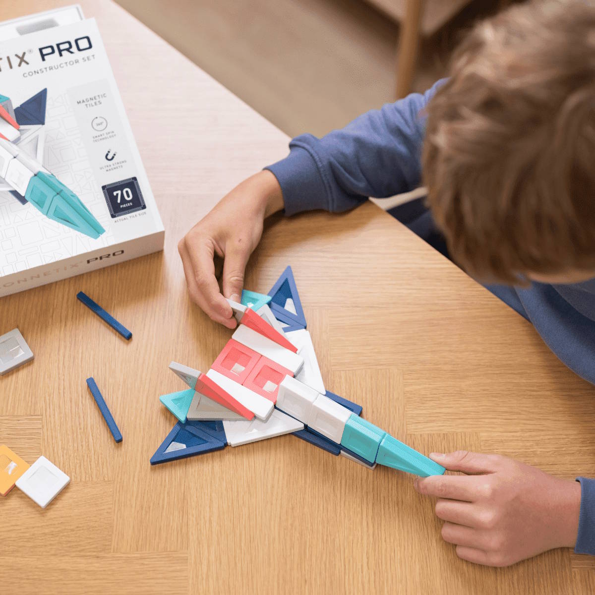 Child playing with a Connetix Pro magnetic construction set on a wooden table