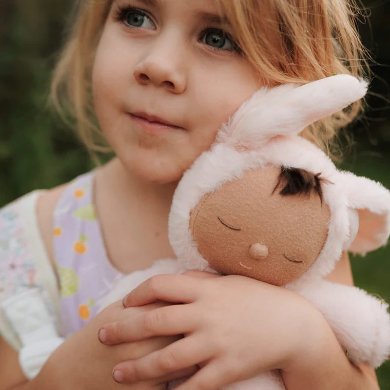 Child cuddling an Olli Ella plush pink bunny rabbit soft toy