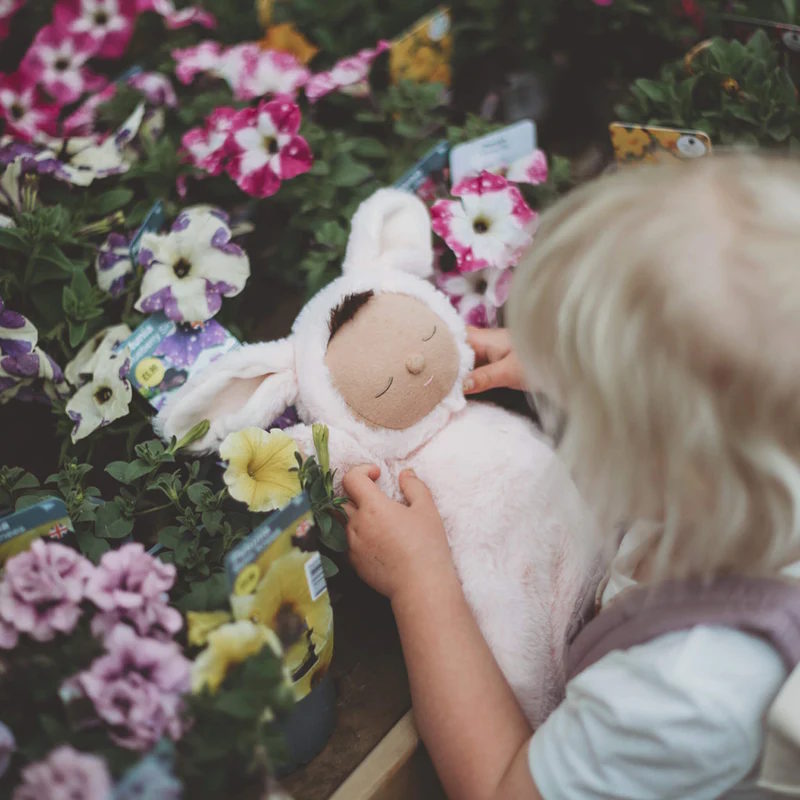 Child holding an Olli Ella bunny soft toy in the garden 