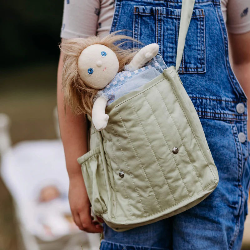 Child holding a green quilted bag with an Olli Ella Dress-Me Dinky doll inside