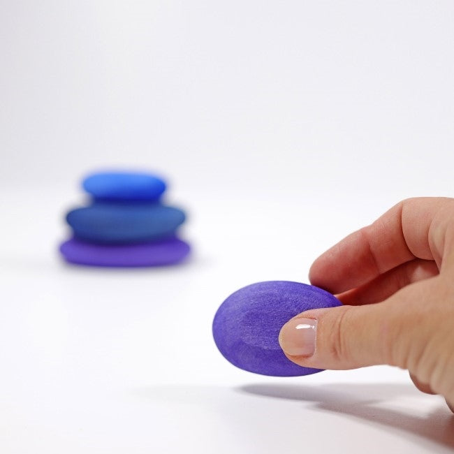 Hand holding smallest of the Grimm&#39;s Dream Pebbles timber stone toy set